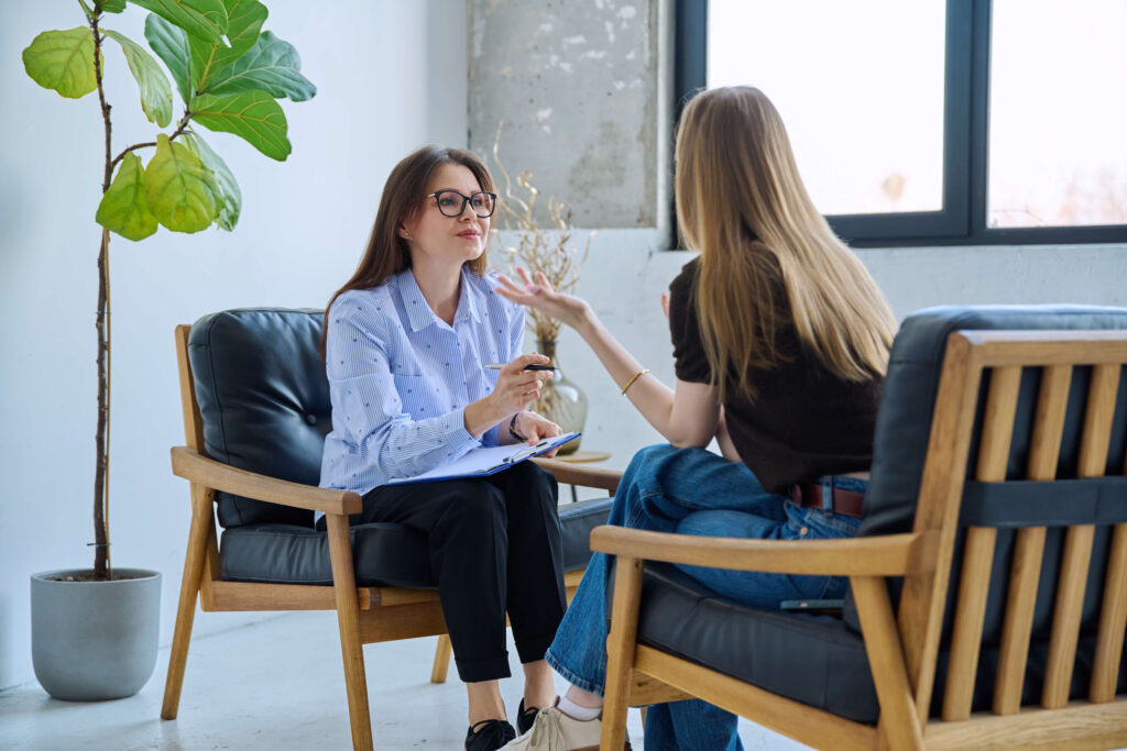 Female professional mental specialist, therapist working with patient young woman in office